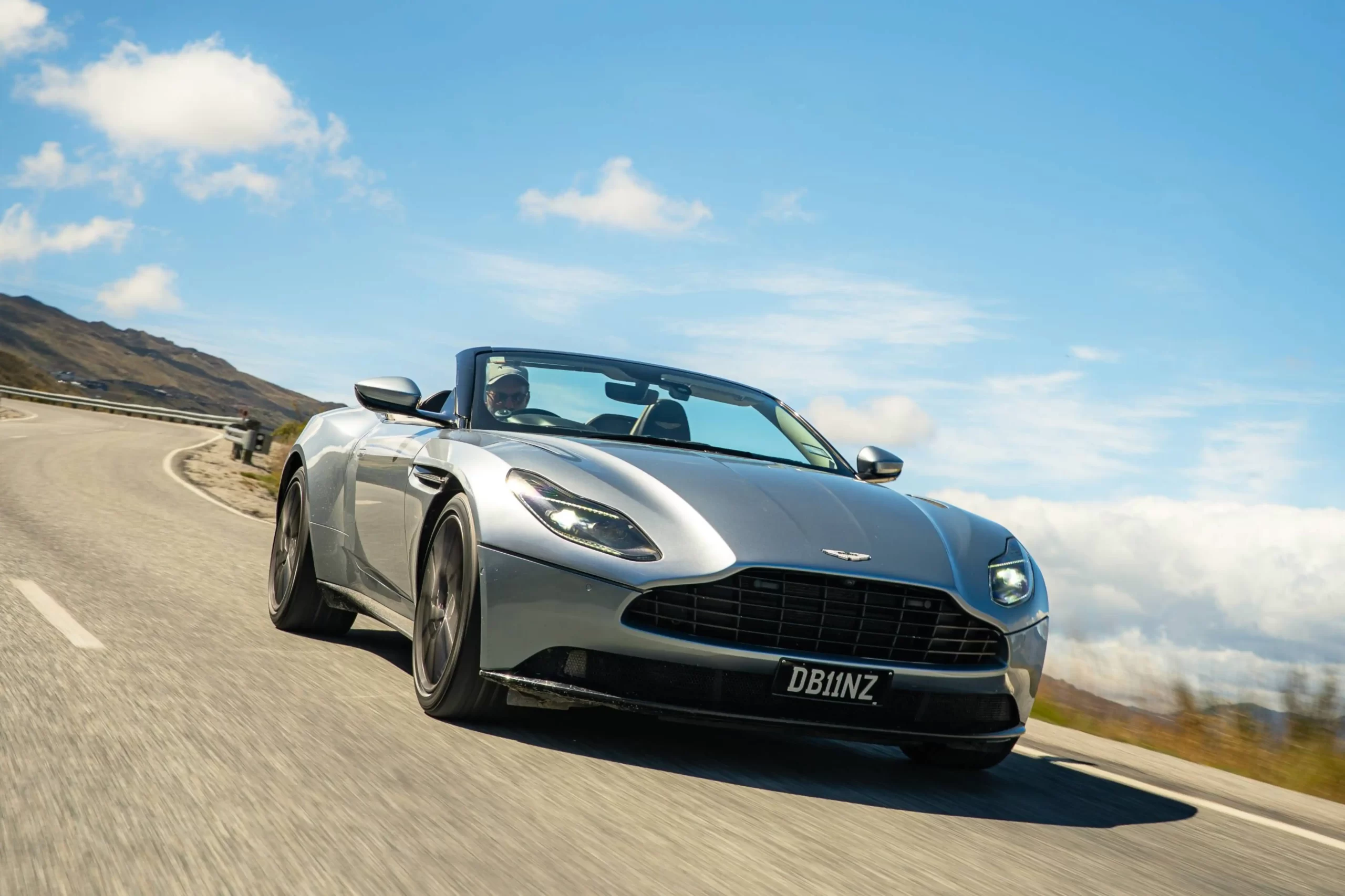 An Aston Martin DB11 Volante at speed on an open New Zealand highway